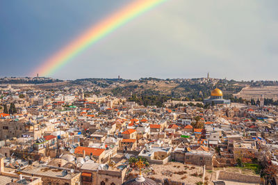 Aerial view of rainbow over town against sky