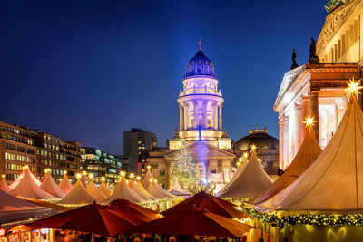 Illuminated buildings against clear blue sky at night