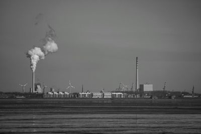 Smoke emitting from factory against sky