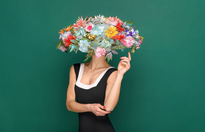 Midsection of woman standing by pink flower against blue background