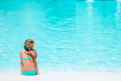 Rear view of woman sitting in swimming pool
