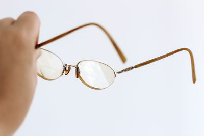 Cropped hand holding sunglasses against white background