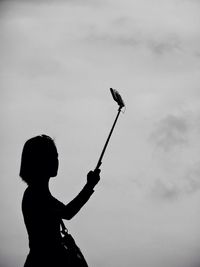 Silhouette woman taking selfie against sky