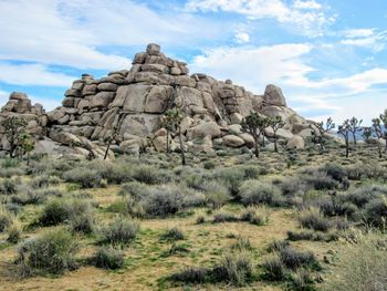 Low angle view of rocks on landscape against cloudy sky