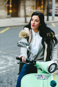 Woman looking away while sitting on motor scooter