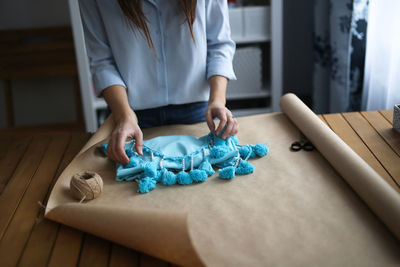 Woman packs a handicraft thing into craft paper, a small business and customer care.