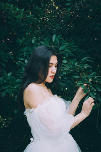 Young woman standing against plants