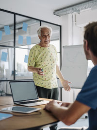 Senior businessman having discussion with colleague while working at office