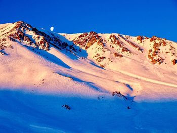 Scenic view of snowcapped mountains against clear blue sky