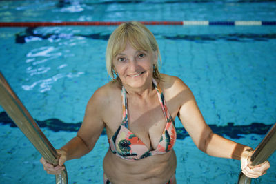 Woman in her 60s swims at public sports pool. slow aging, active lifestyle, health and vitality