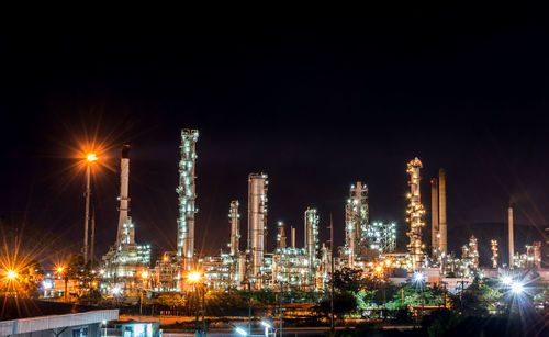 Illuminated smoke stacks against sky at night