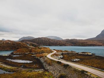 Scenic view of road by mountains against sky