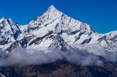 Scenic view of snowcapped mountains against clear blue sky