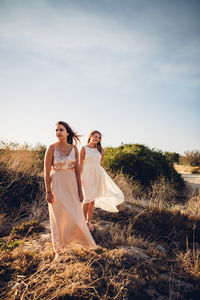 Full length of happy woman standing on field against sky