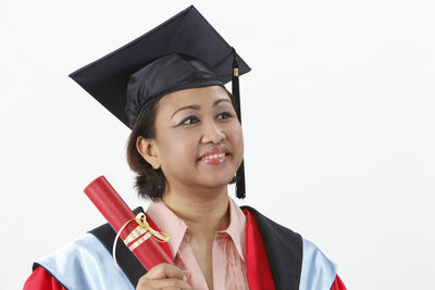 Happy woman in graduation gown against white background