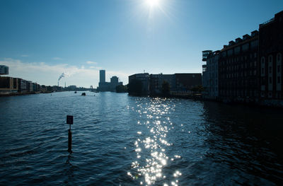 Sun shining over river in city