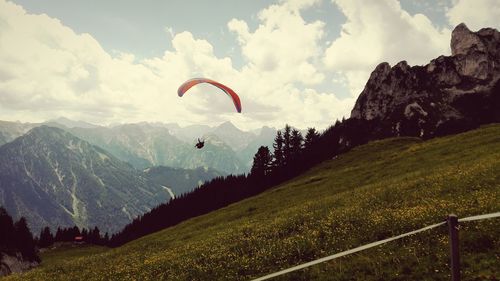 Person paragliding against mountains