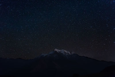 Low angle view of silhouette mountain against sky at night