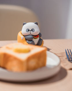 A toy panda shifting its attention to the delicious toast in front of it