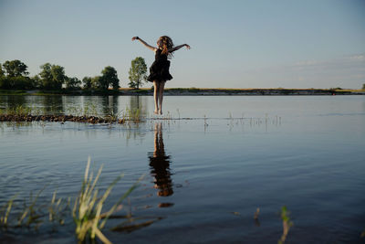 Teenage girl standing in lake against sky