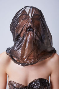 Young woman wearing plastic on face against white background