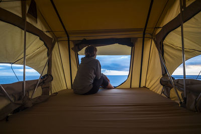 Rear view of woman sitting in tent against sea