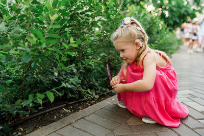 Side view of young woman standing against plants