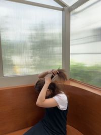 Woman tying hair sitting on seat