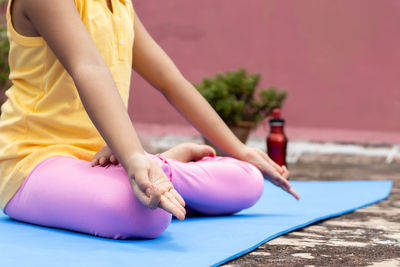 Close up of an indian girl child practicing yoga on yoga mat outdoors
