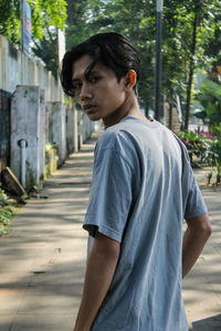 Side view of young man looking away while standing outdoors