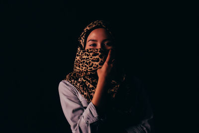 Close-up of young woman against black background