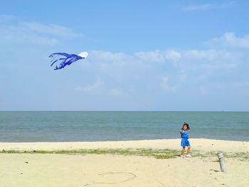 Woman on beach umbrella by sea against sky
