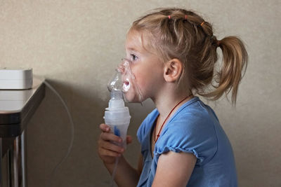 Portrait of boy drinking water against wall