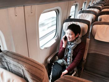 Woman talking on mobile phone while sitting in train