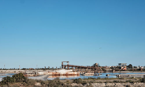 Buildings by sea against clear blue sky