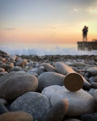 Stones on beach against sky during sunset