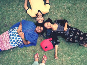 High angle portrait of smiling friends lying down on field