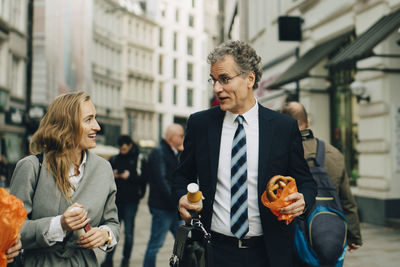 Businessman and businesswoman with meal walking in city