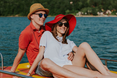 Young woman wearing sunglasses sitting on boat against sea