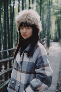 Portrait of woman wearing warm clothing standing on footpath at forest