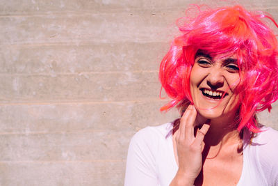 Portrait of cheerful young woman with pink hair against steps