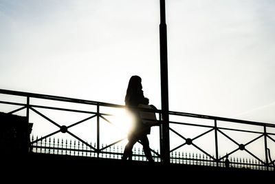 Silhouette woman standing on bridge against sky