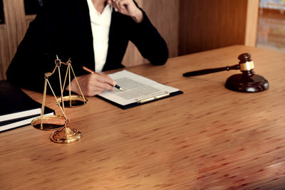 Midsection of lawyer writing on document at table in office
