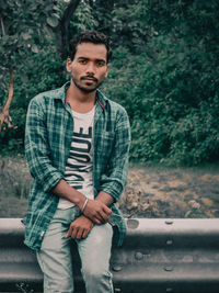 Portrait of young man standing against trees