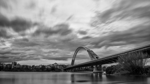 Bridge over river against sky in city