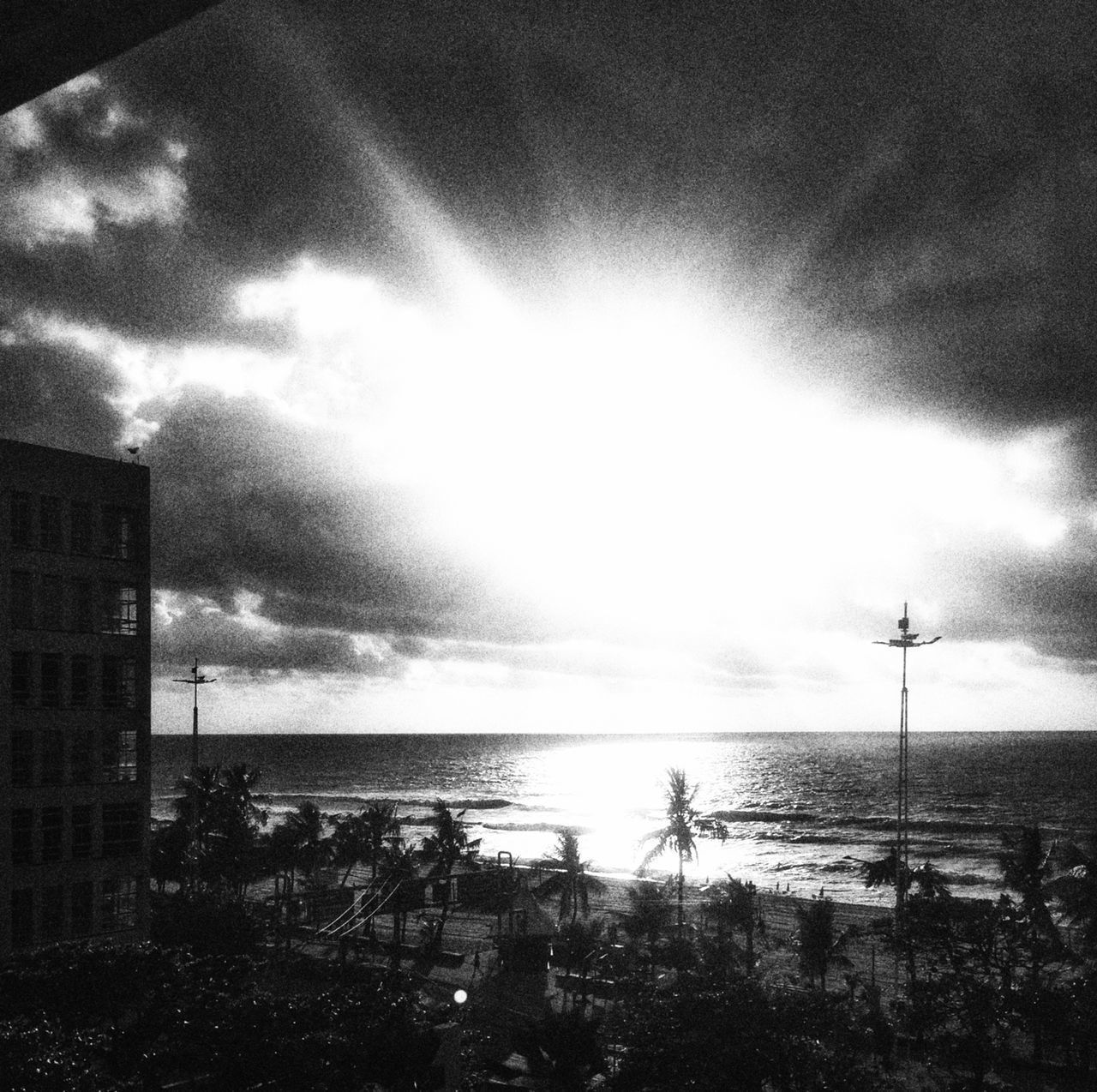 SILHOUETTE BUILDINGS BY SEA AGAINST SKY IN CITY