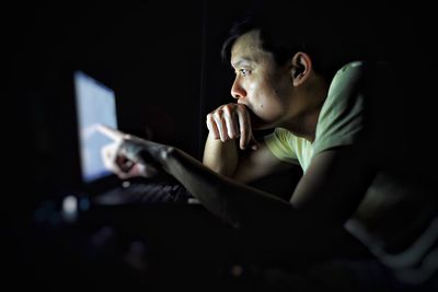 Portrait of teenage boy sitting in dark room