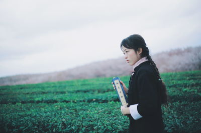 Side view of young woman looking at field