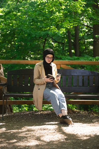 Young woman sitting on bench in park