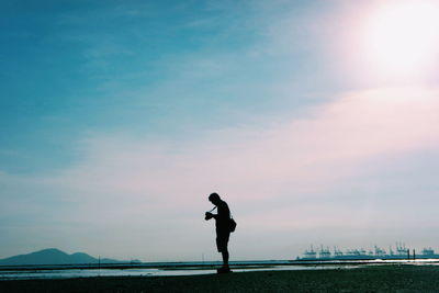 Silhouette man standing by sea against sky during sunset